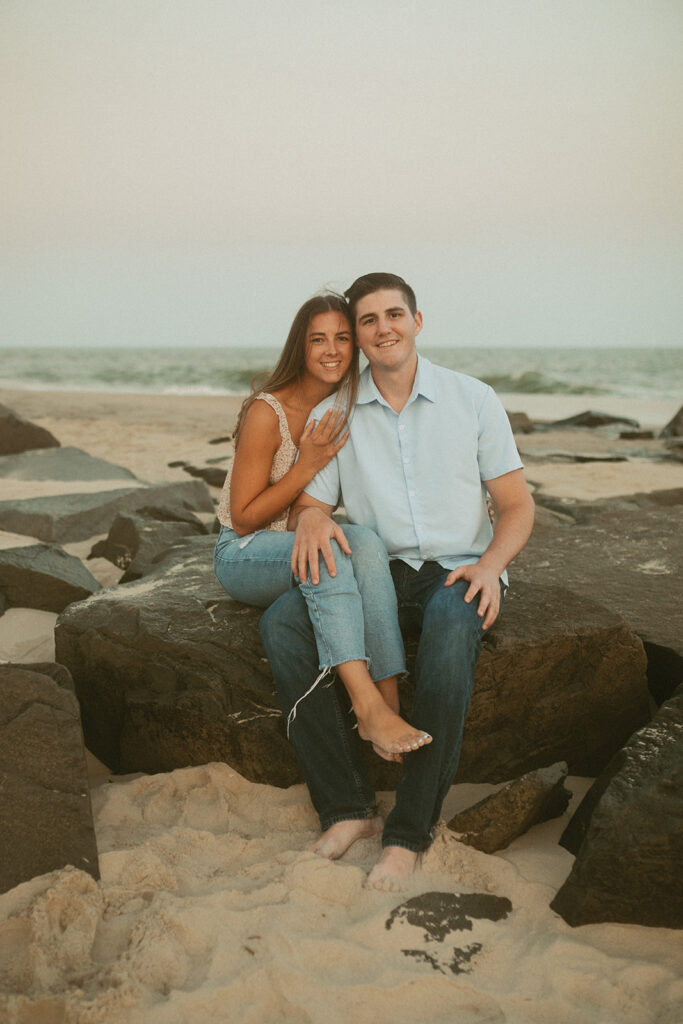 Cape May New Jersey beach engagement photos couple sitting on rocks