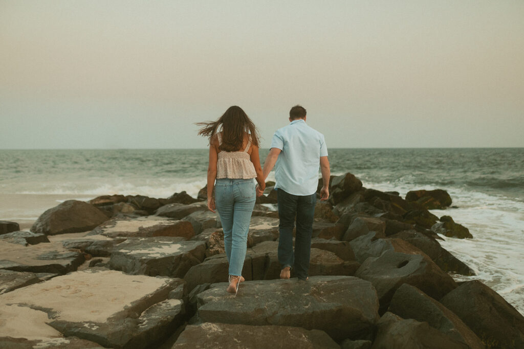 Cape May New Jersey beach engagement photos couple walking on rocks