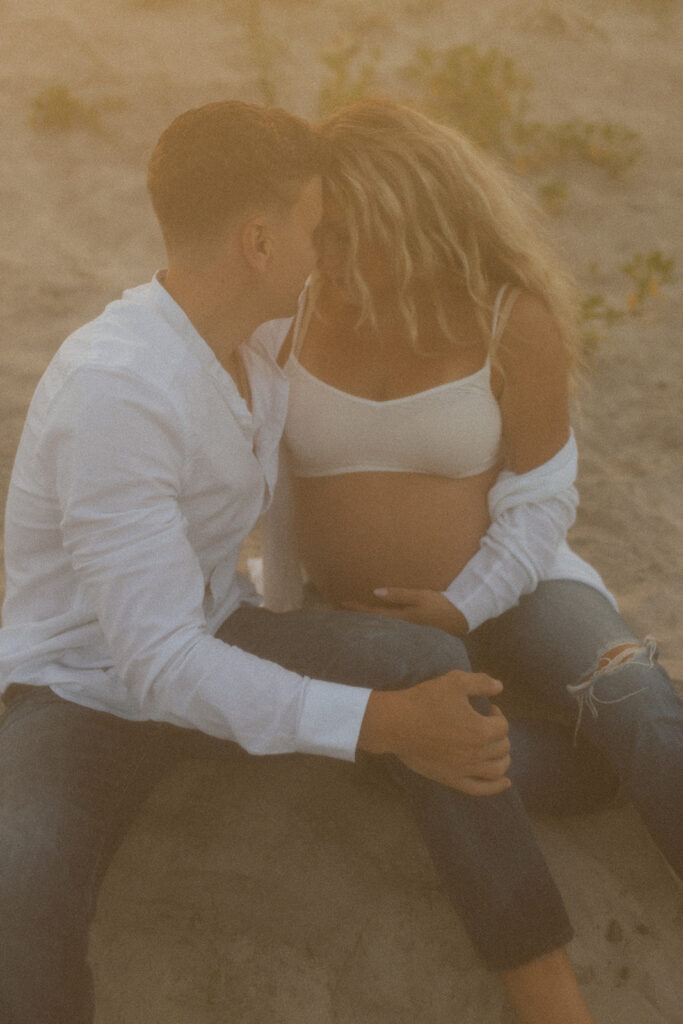 New Jersey Maternity maternity session couple sitting on ground looking at each other holding baby belly